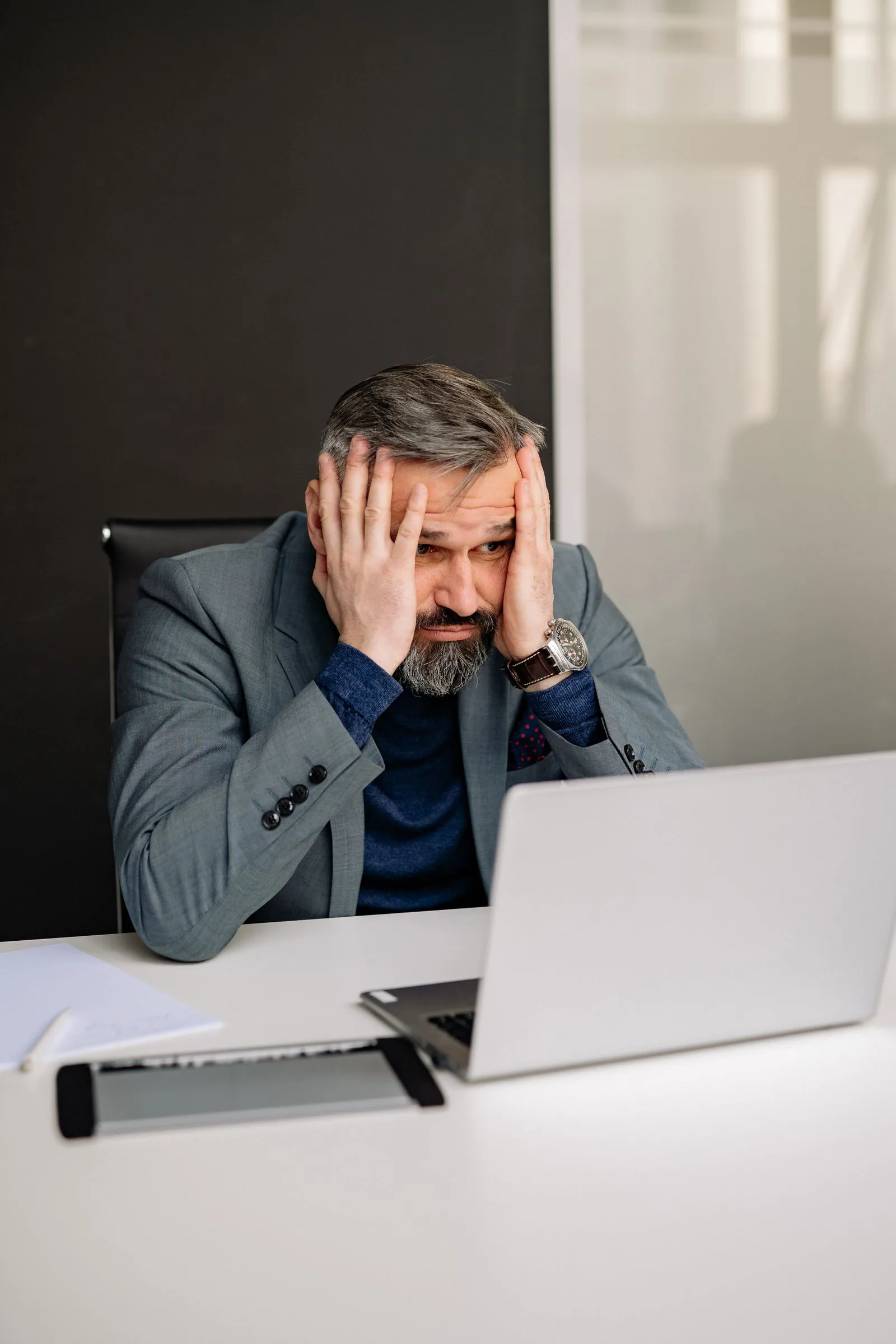Commercial manager pressing his temples while staring at a screen